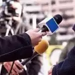 stock image of a reporters holding microphones pointed a person you cannot fully see