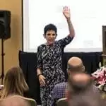 Glenna Hecht with her left hand raised in the air. She was speaking at an SAF event in 2015
