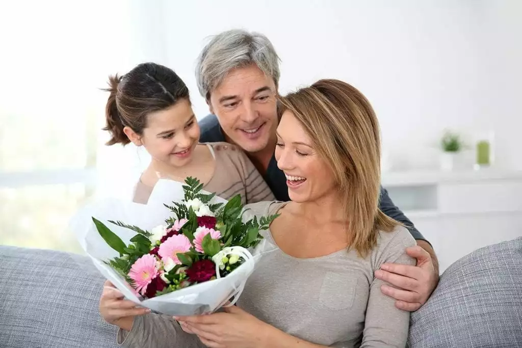 husband and daughter presenting flowers to the wife, mother