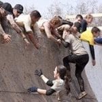 People helping others climb a wall