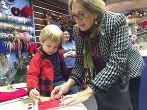 Cathy Herrold (in back), co-owner of Graci's Flowers & Gifts, supervises while one of her best customers, County Commissioner Peggy Chamberlain Roup, helps her grandson decorate a stocking during Santa Fest, an annual tradition in Sellinsgrove, Pennsylvania. 