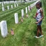African American female child standing in front of a gravestone at the National Memorial Cemetary, Arlington, Virginia