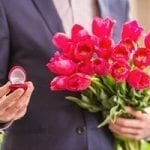Man holding flowers and engagement ring