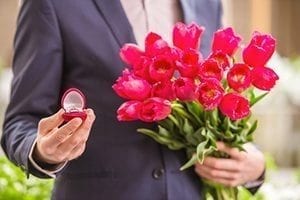 Man holding flowers and engagement ring