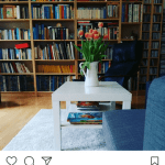 livingroom, white table, blue chair, books on a self, white rug