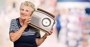 Old Caucasian lady holding a radio to her ear.