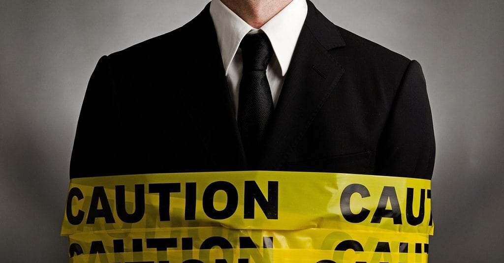 man in a black suit with caution tape wrapped around him.