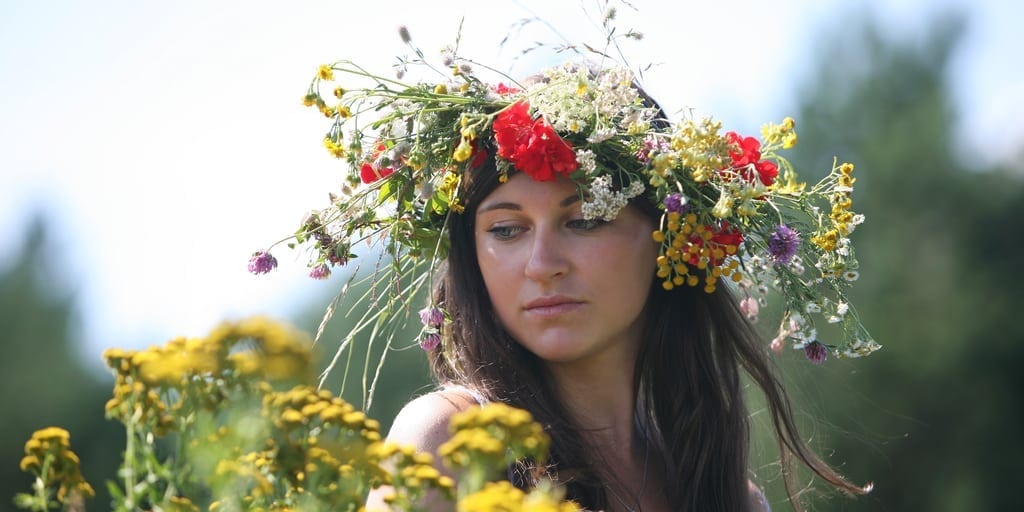 midsummer solstice themed image with a Caucasian female outside with a flower crown on