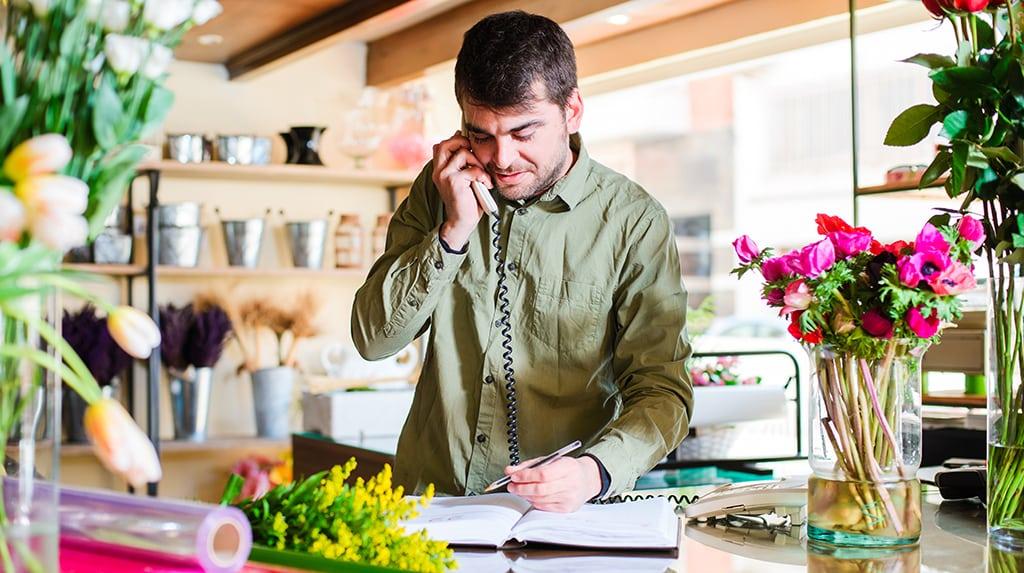 Caucasian man answering the phone in a retail flower shop